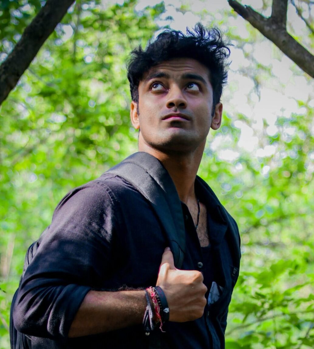 Casual young man with backpack exploring a green forest in daylight.